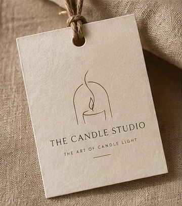 A Candle Studio hang tag tied with twine, resting on natural linen